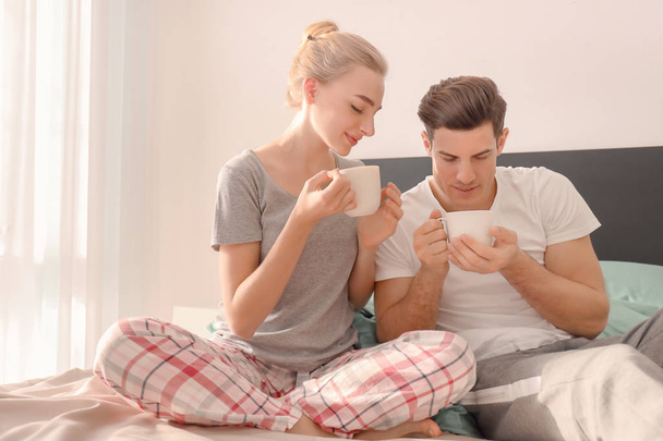 Young lovely couple drinking coffee on bed - Zdjęcie, obraz