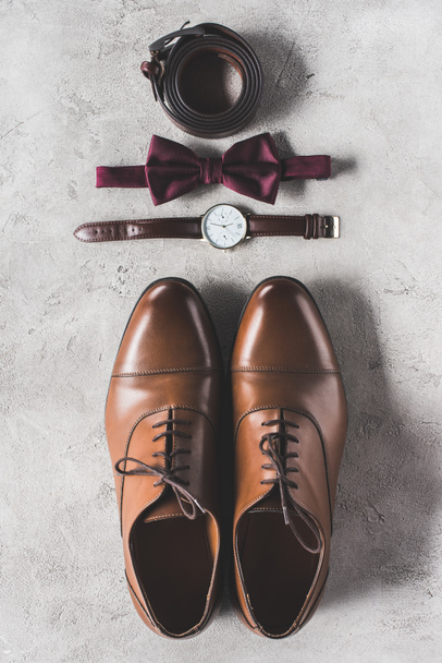 top view of pair of wedding shoes, bow tie and wristwatch on gray surface - Fotoğraf, Görsel