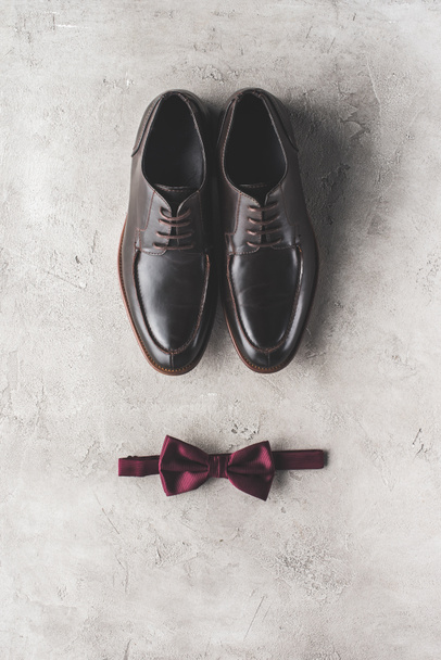 vista superior de par de zapatos de boda negros y pajarita en superficie gris
 - Foto, Imagen