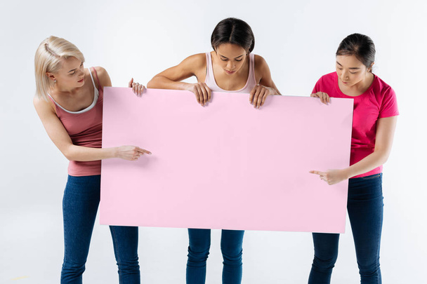 Hyvännäköiset fiksut naiset katselevat julistetta
 - Valokuva, kuva