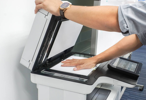 Close-up van zakenman gebruik printer glasplaat te scannen op belangrijke en vertrouwelijke documenten in office - Foto, afbeelding