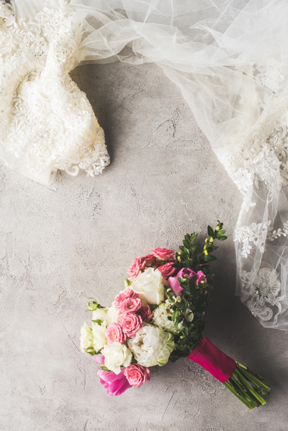 top view of wedding dress and bouquet on gray surface - Fotoğraf, Görsel
