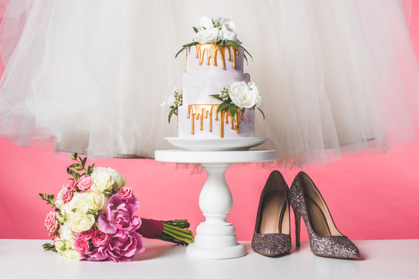 pair of shoes, wedding bouquet, cake and white dress isolated on pink - Photo, Image