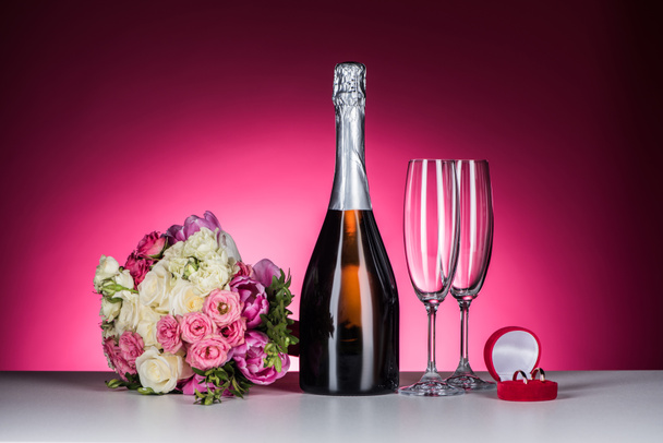 結婚式のブーケ、結婚指輪、ピンクのテーブルの上のシャンパン - 写真・画像