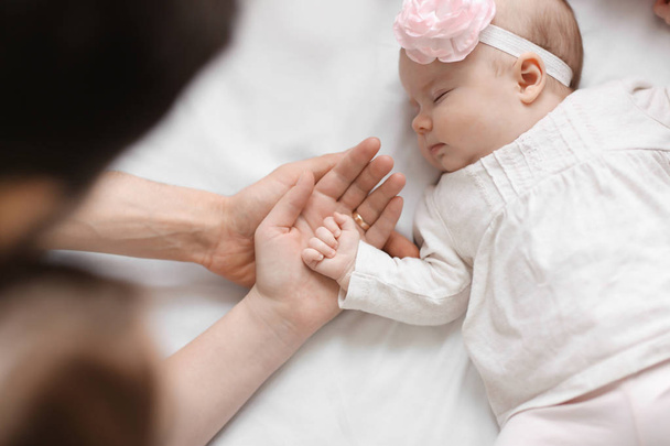 Parents holding baby's hand on bed - Fotoğraf, Görsel