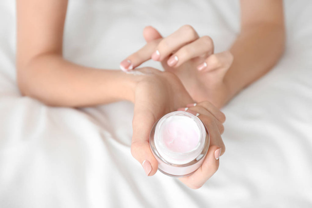 Young woman with jar of hand cream at home, closeup - Photo, Image