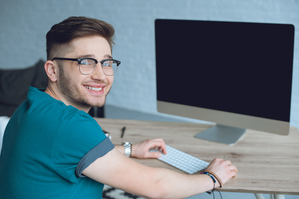 Smiling designer working by table with desktop computer - Photo, Image