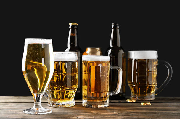 Vidros diferentes com cerveja na mesa de madeira contra fundo preto
 - Foto, Imagem
