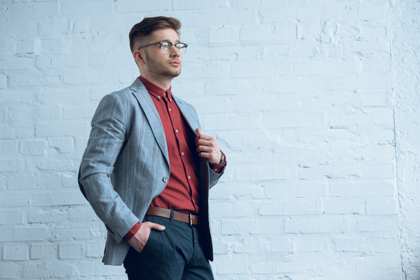 Hombre con estilo en ropa casual con gafas de pared de ladrillo
 - Foto, imagen