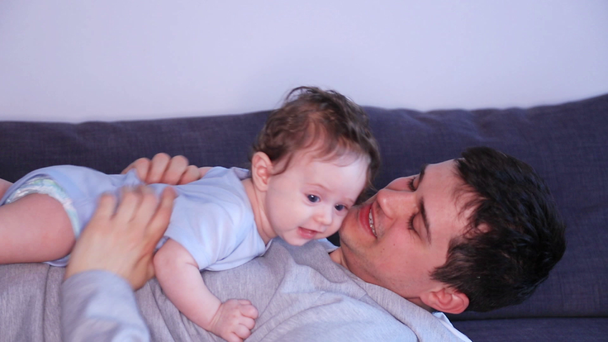 Ευτυχής πατέρας τοποθέτηση στο κρεβάτι κρατώντας και φιλιά μικρό γιο - Πλάνα, βίντεο