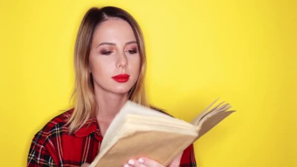 Pretty woman reading book on yellow background - Filmati, video