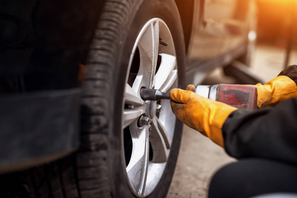 Automechaniker Mann mit Elektroschrauber wechselt Reifen in Garage  - Foto, Bild