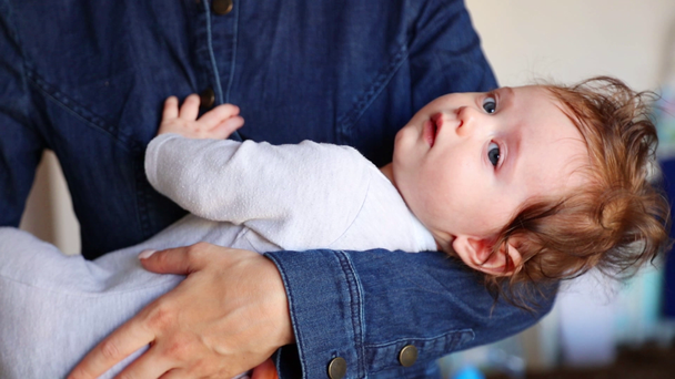 Обрезанный вид женщины в джинсовой блузке, держащей маленького мальчика в руках
 - Кадры, видео
