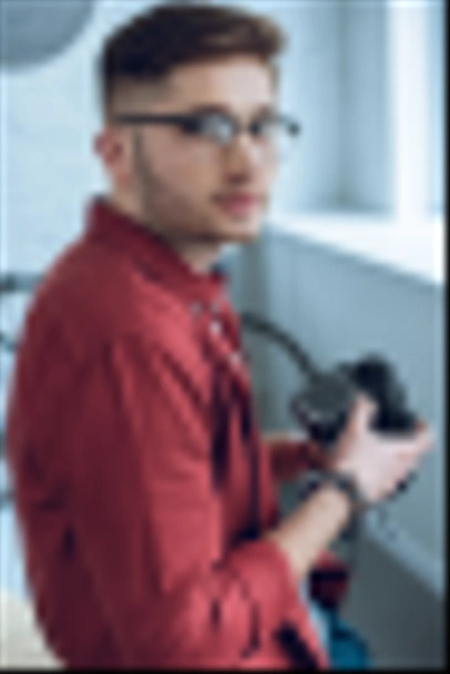 Bearded man holding digital camera by light window - Foto, imagen