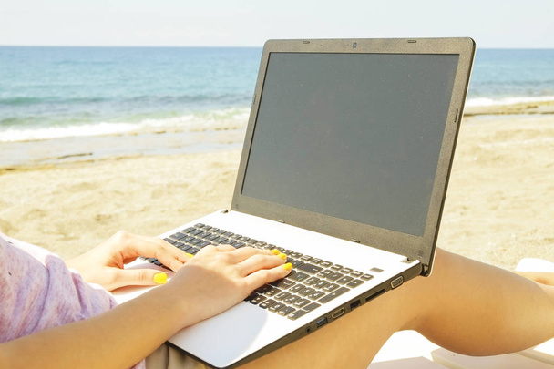 Молода блондинка працює на ноутбуці на пляжі в сонячний день. Крупним планом жіночі руки друкують на білому ноутбуці комп'ютерний ноутбук, блог, копірайтинг. Крупним планом, місце для копіювання
. - Фото, зображення