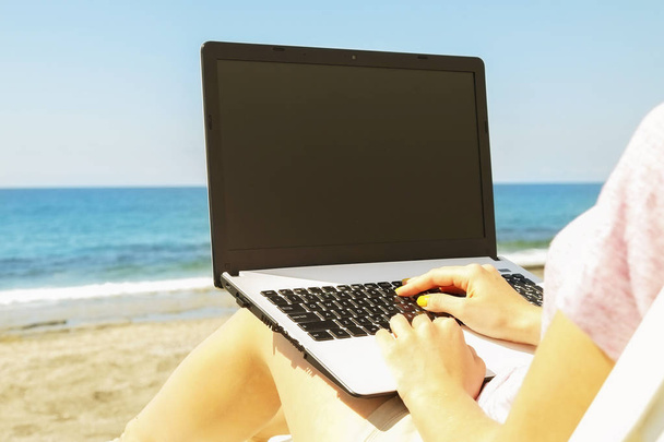 Молода блондинка працює на ноутбуці на пляжі в сонячний день. Крупним планом жіночі руки друкують на білому ноутбуці комп'ютерний ноутбук, блог, копірайтинг. Крупним планом, місце для копіювання
. - Фото, зображення