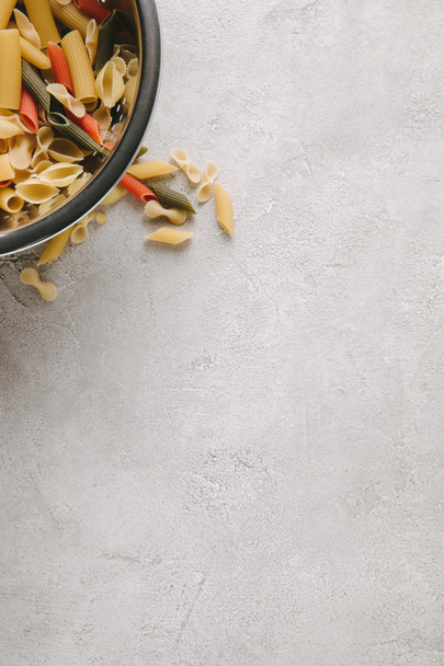 top view of raw pasta in bowl on concrete tabletop - Fotó, kép