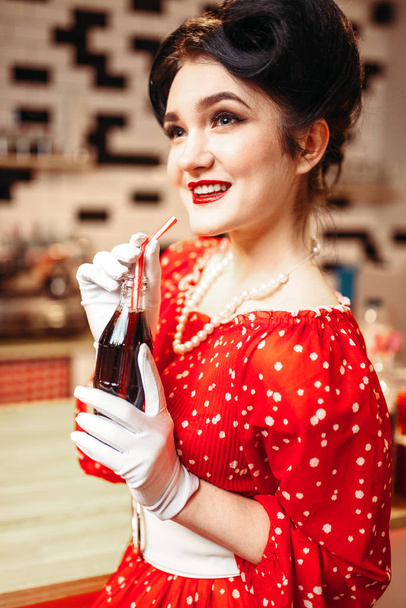 ピンナップ女性飲む炭酸飲料水玉柄, ビンテージ スタイルのレトロなカフェ、赤色のドレスで - 写真・画像