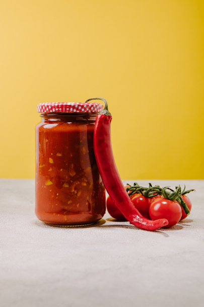 canned ketchup with chilli pepper and cherry tomatoes on concrete surface - Foto, Bild