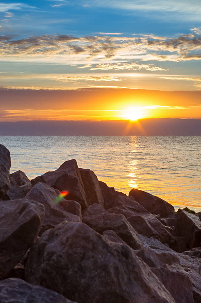 costa de piedra contra el mar, puesta de sol, nubes, composición vertical
 - Foto, Imagen