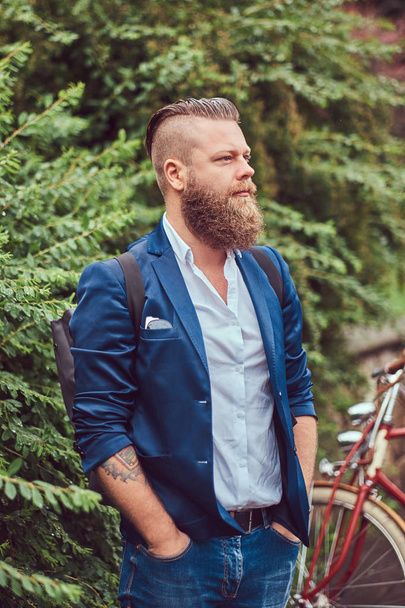 Masculino vestido com roupas casuais, de pé com uma bicicleta retro em um parque
. - Foto, Imagem