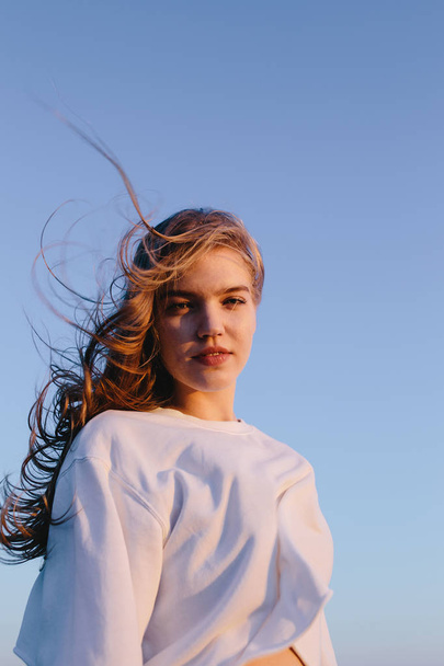 portrait of beautiful young woman outdoor on background of sky on sunrise. Pretty girl teenager on nature. Copy space. Freedom, romantic, fashion, wellness, healthy concept - Foto, immagini