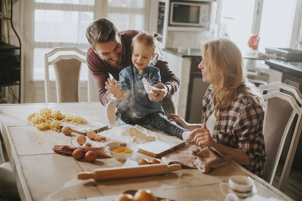 Ευτυχισμένη οικογένεια κάνοντας τα ζυμαρικά στην κουζίνα στο σπίτι - Φωτογραφία, εικόνα