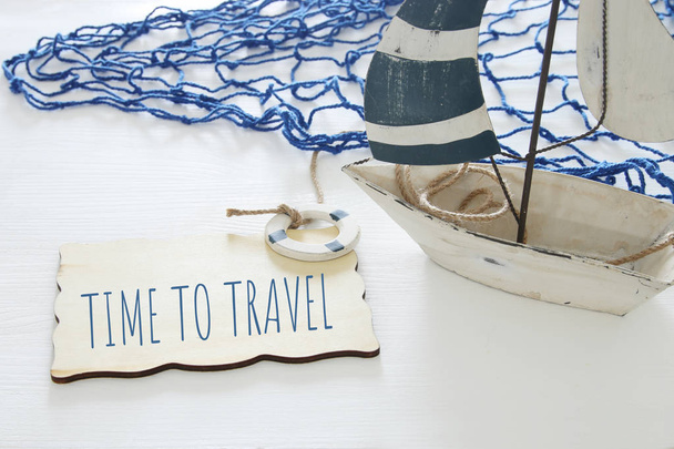 морське концептуальне зображення з білим декоративним вітрильним човном і текстом над дерев'яною дошкою: TIME TO TRAVEL
. - Фото, зображення