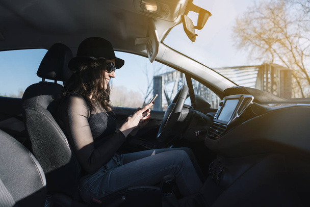 Gyönyörű fiatal nő, a mobiltelefon használata az autóban - Fotó, kép