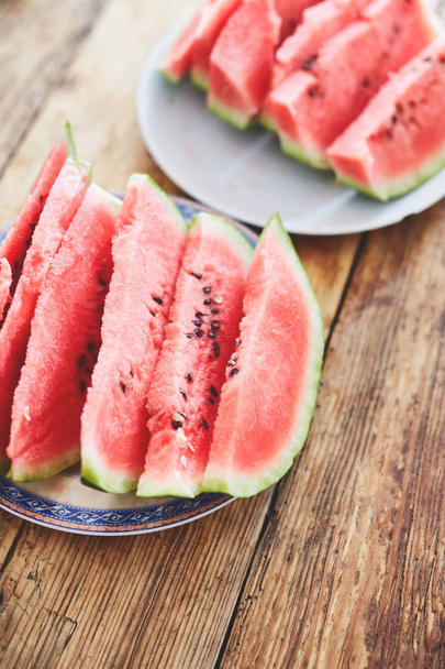 sliced slices of watermelon lie on a plate on a wooden table - Foto, immagini