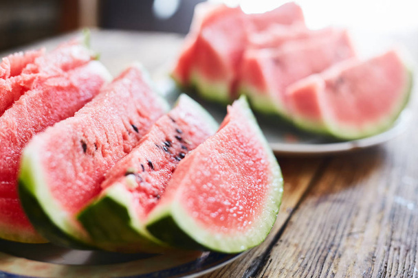 sliced slices of watermelon lie on a plate on a wooden table - Φωτογραφία, εικόνα