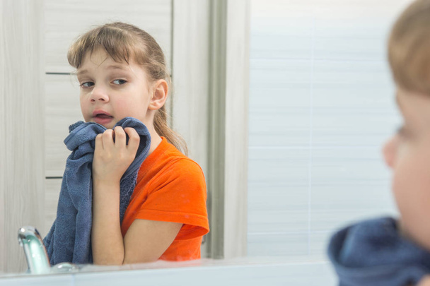 Ragazza di sette anni si pulisce il viso con un asciugamano dopo il lavaggio
 - Foto, immagini