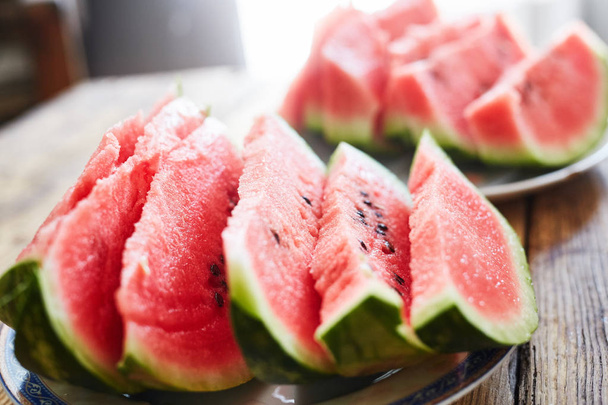 sliced slices of watermelon lie on a plate on a wooden table - Φωτογραφία, εικόνα