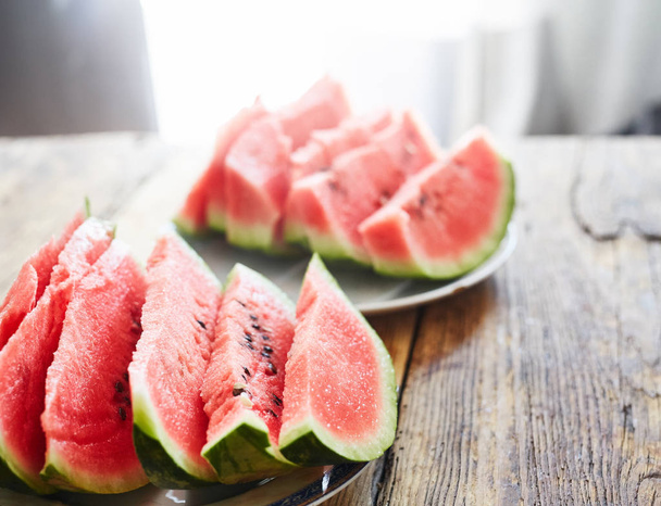 sliced slices of watermelon lie on a plate on a wooden table - Foto, imagen