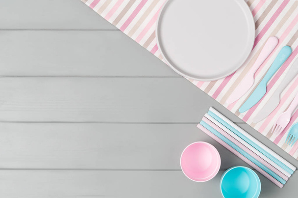 Kids pastel plastic tableware isolated on gray background. Top view - Zdjęcie, obraz