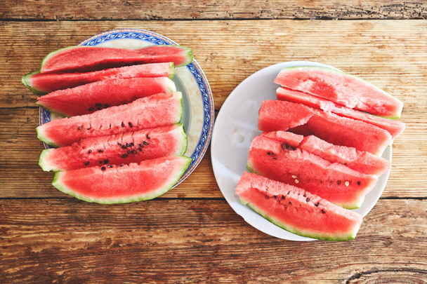 sliced slices of watermelon lie on a plate on a wooden table - Photo, image