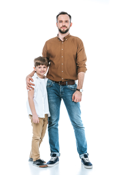 full length view of happy father and son standing together and smiling at camera isolated on white - Photo, image