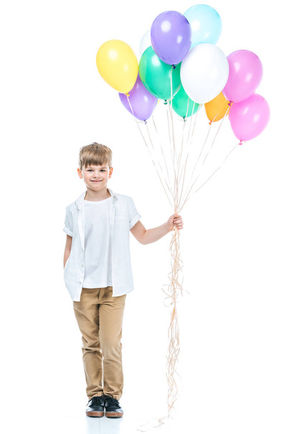 adorable little boy holding colorful balloons and smiling at camera isolated on white - Photo, Image