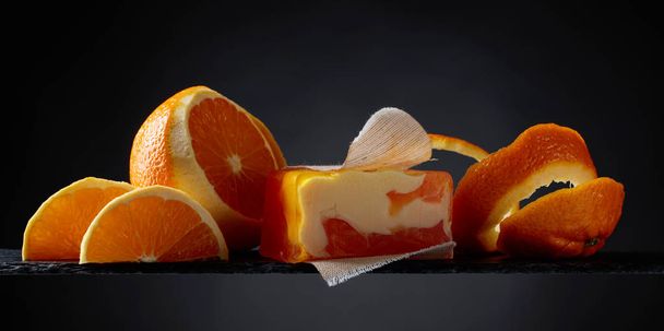 Bar of natural organic soap with orange on black background.  - Foto, afbeelding