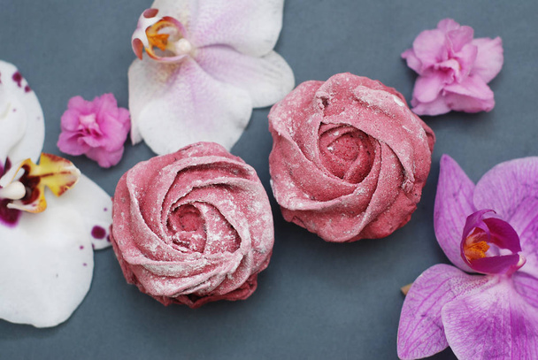 Sweet Pink Meringues on Blue Gray background with Orchid Flowers. Spring Background. Copy space. Breakfast. - Fotografie, Obrázek