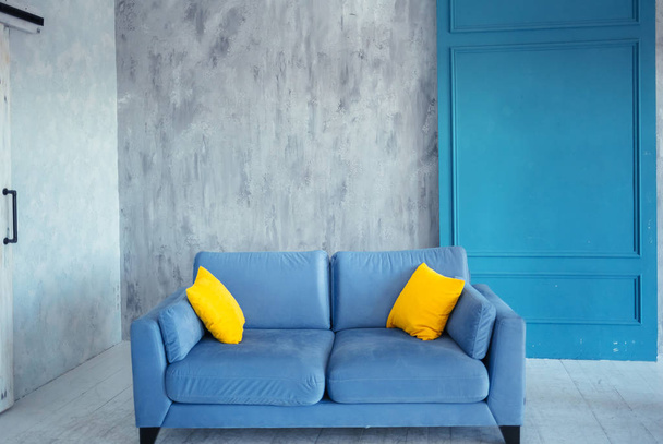 Niebieski Nowoczesna sofa i dwa żółte poduszki w komfortowy apartament - Zdjęcie, obraz