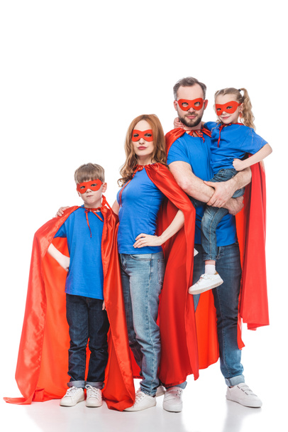 Super familie in maskers en mantels permanent samen en kijken naar camera geïsoleerd op wit  - Foto, afbeelding