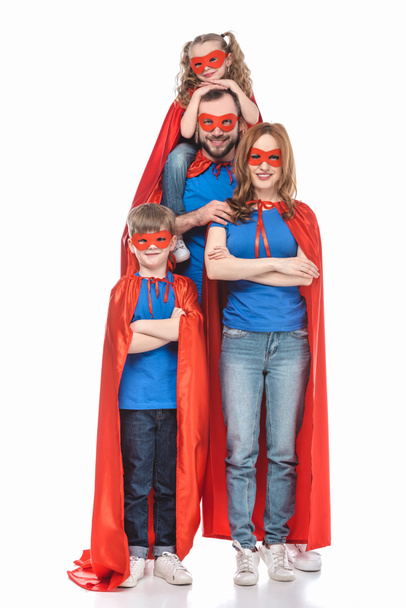 cheerful super family in masks and cloaks smiling at camera isolated on white  - Photo, Image