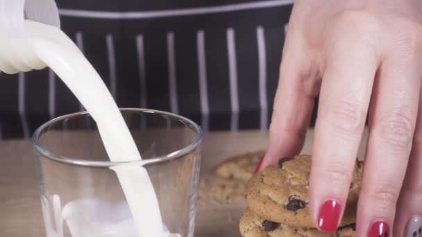 Womans hand takes a cookie and pours milk - Footage, Video