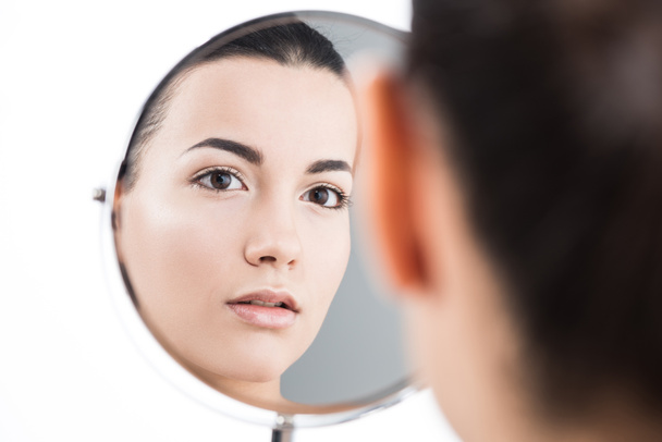 Вид сзади красивой девушки, смотрящей в зеркало, изолированное от белого
 - Фото, изображение