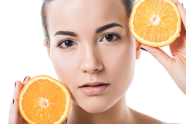 menina nua atraente com pele limpa segurando pedaços de laranja isolados no branco
 - Foto, Imagem