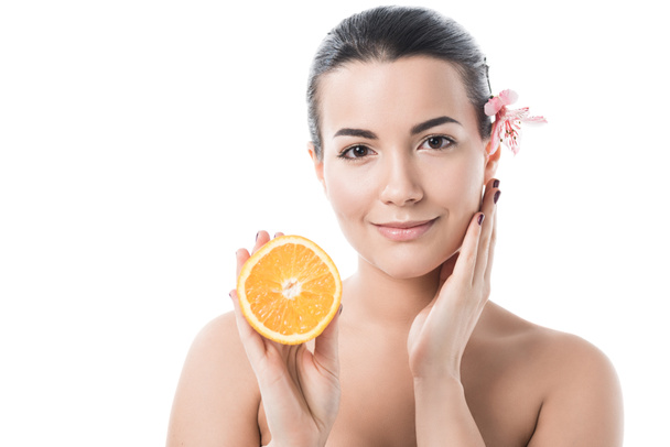 atraktivní nahá dívka s čistou kůží drží pomeranč a dotýkání tváře izolované na bílém - Fotografie, Obrázek
