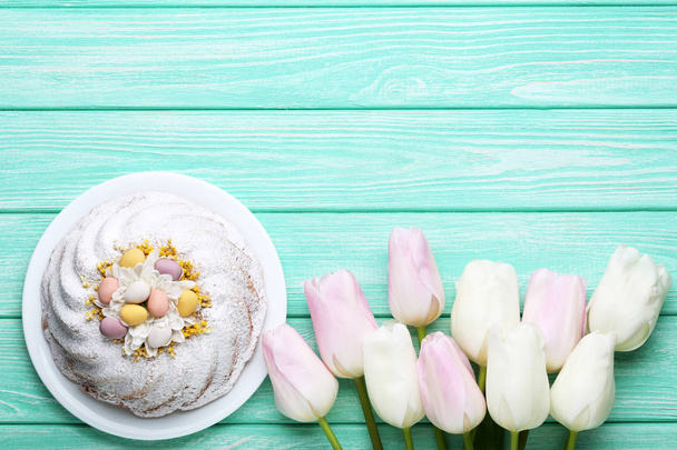 Easter cake in plate with tulip flowers on mint wooden table - 写真・画像