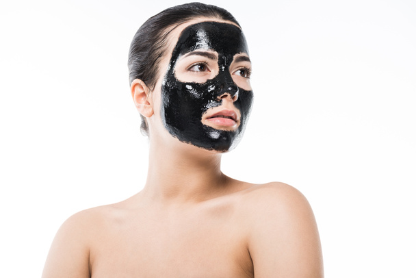 beautiful girl in cosmetic black clay facial mask looking away isolated on white - Valokuva, kuva