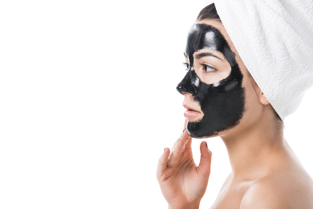 side view of beautiful girl in cosmetic black clay facial mask isolated on white - 写真・画像